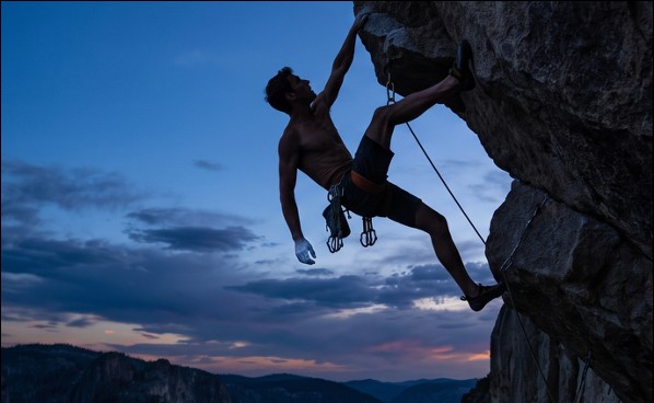 A climber committing to a hard move at dusk